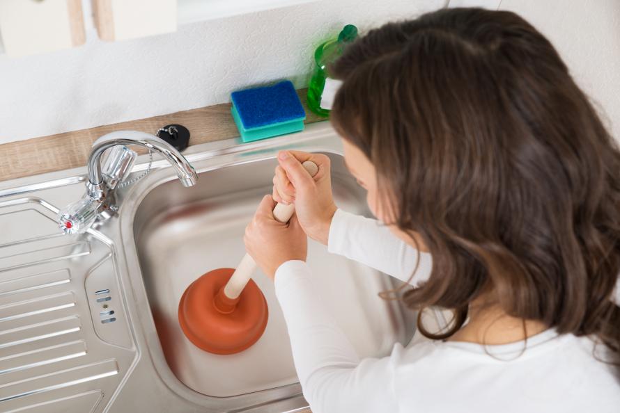 Kvinna med vaskrensare (sugkoppsverktyg) löser stopp i vasken