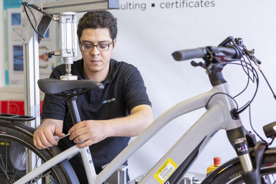 Redouane Bouassaba, testtekniker på velotech.de, justerar elcykeln i testriggen eRig. Här testas räckvidd och prestanda. Foto: Stefan Ernst.