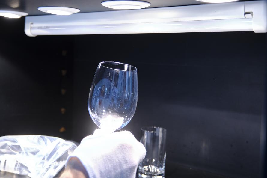 Grå hinna på glas och bestick efter disk bedöms i laboratoriets ljuskammare. Foto: Tobias Meyer